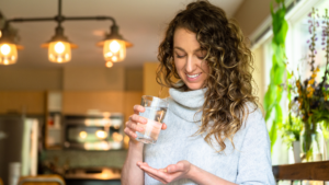 Woman holding her supplements and a glass of water
